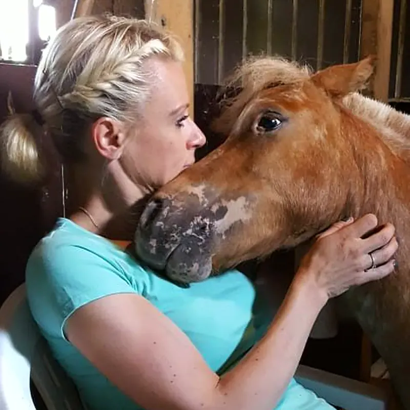 Sonja Blatton schmiegt ihren Kopf an ein Pony im Stall